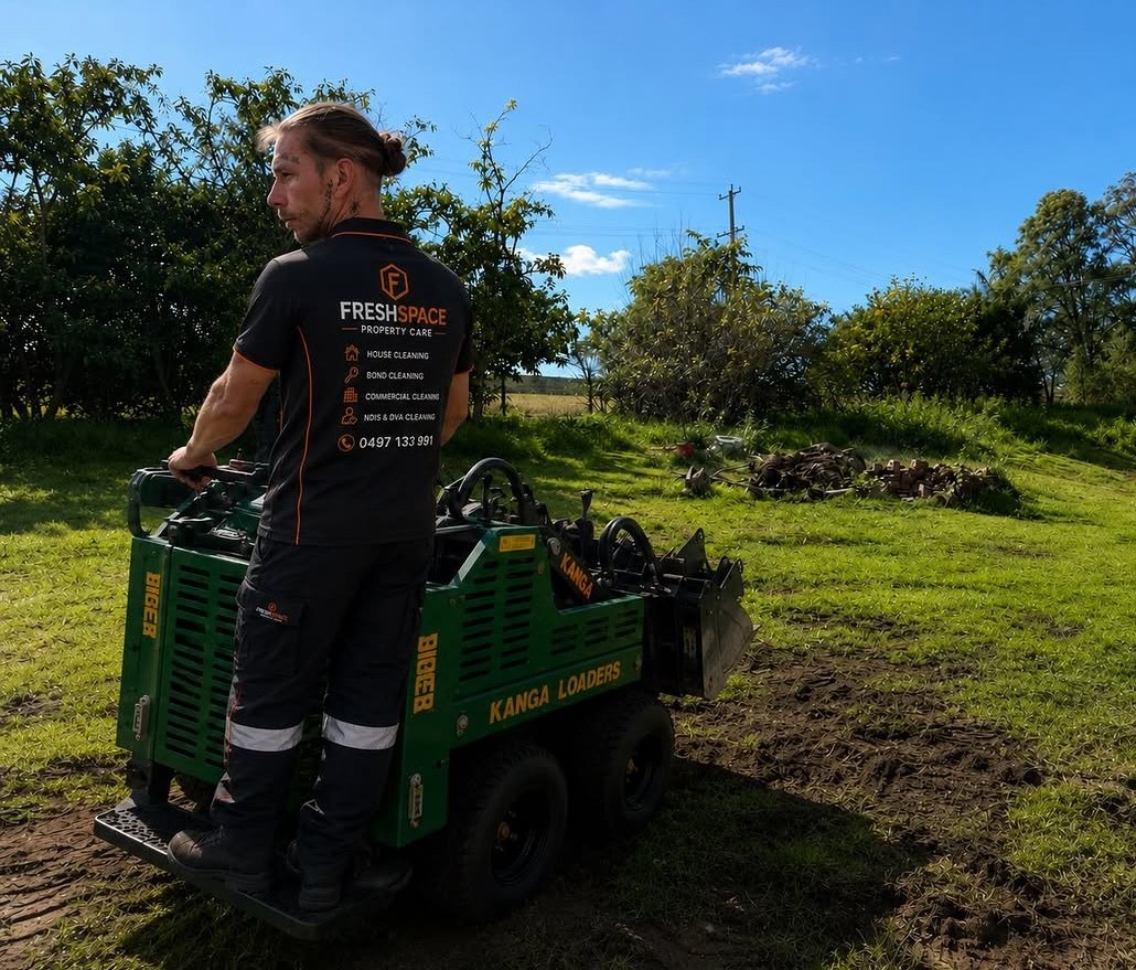 FreshSpace team member operating a compact loader on an outdoor property